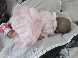 A beautiful Reborn baby girl in a lovely white and pink dress and pink matching